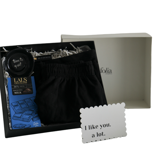 A thoughtful gift for him; this curated box includes black shorts for relaxation, a witty ashtray, a sleek lighter, and decadent chocolate bar from Raco or Lals.